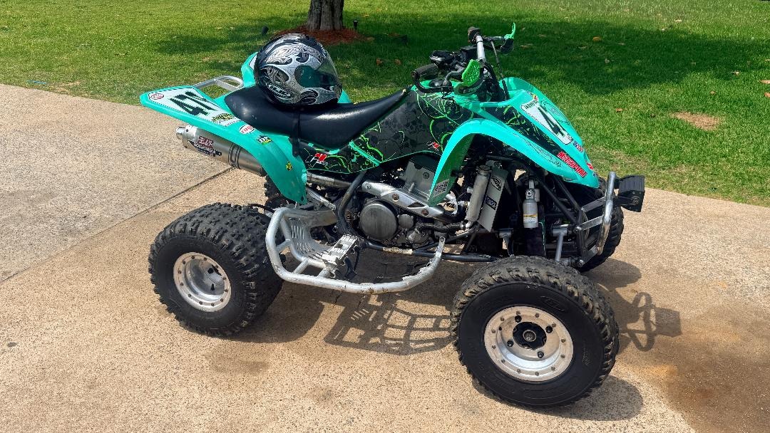 Turquoise and green sport four-wheeler parked on a driveway